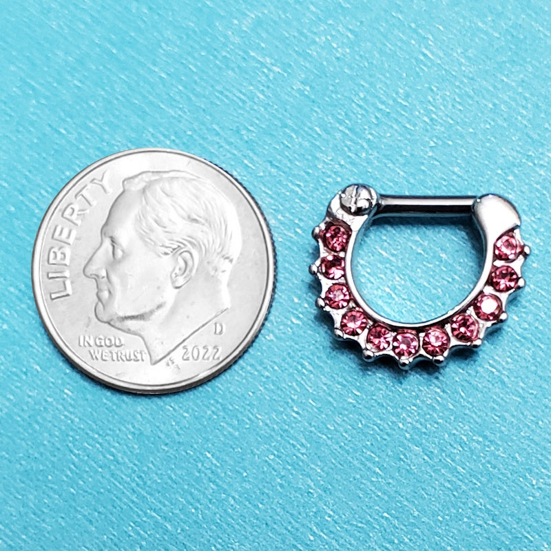 A 14 gauge septum clicker pictured on an aqua background next to a dime for a size comparison.