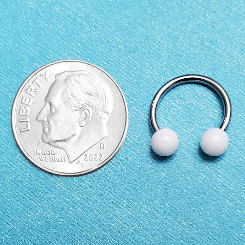 A 16 gauge horseshoe septum ring pictured on an aqua background next to a dime for a size comparison.