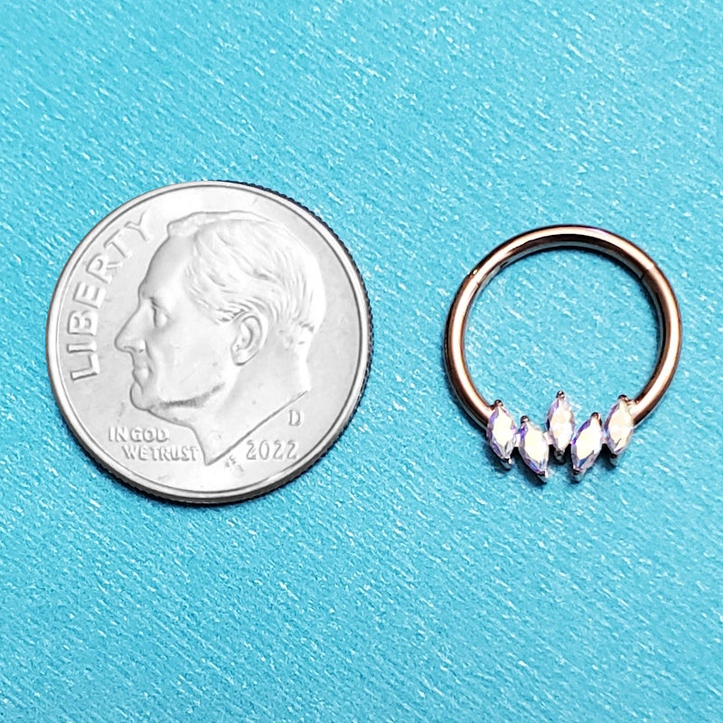 A 16 gauge segment ring pictured on an aqua background next to a dime for a size comparison.