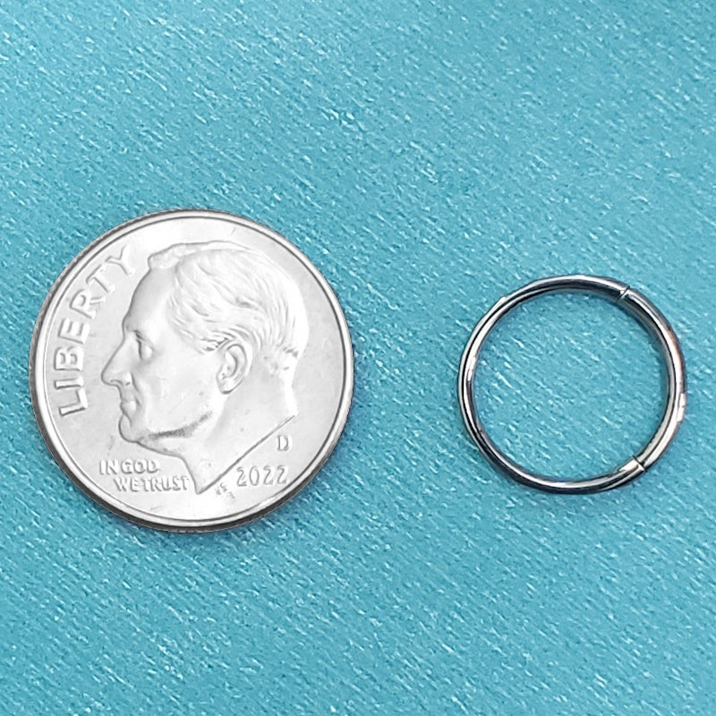 A 16g titanium septum hoop pictured on an aqua background next to a dime for a size comparison.