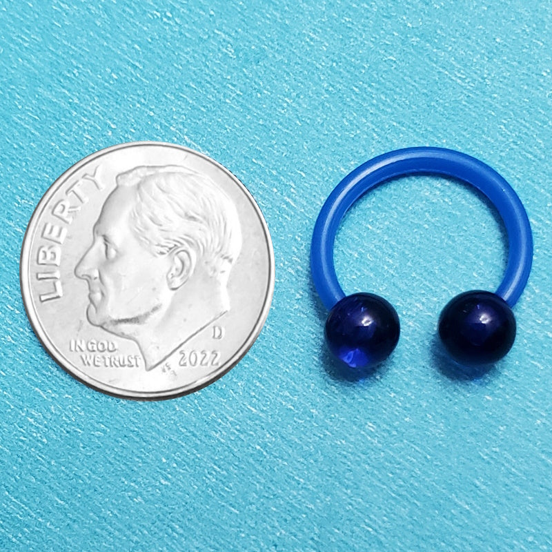 An acrylic blue septum ring pictured on an aqua background next to a dime for a size comparison.