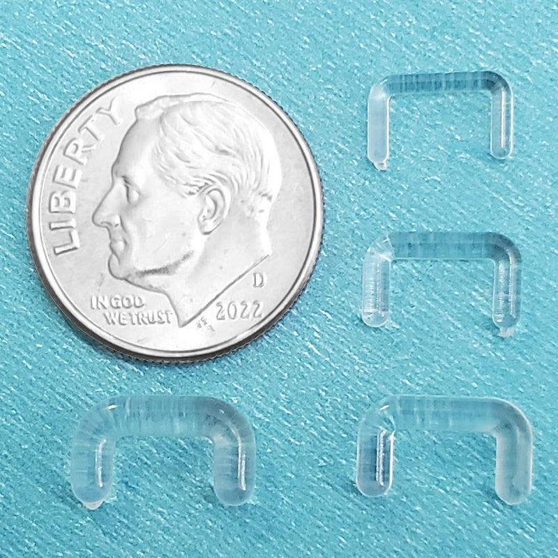 Four sizes of acrylic clear septum retainers pictured on an aqua background next to a dime for a size comparison.