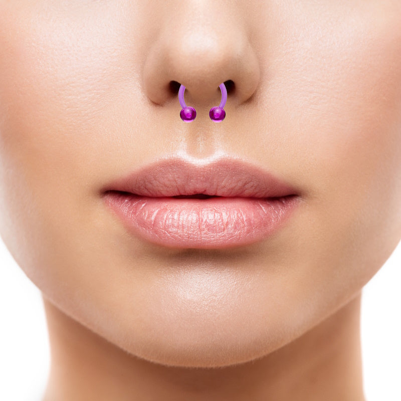 An acrylic purple septum ring featuring a horseshoe shape with a ball on each end pictured in the septum piercing of a woman.