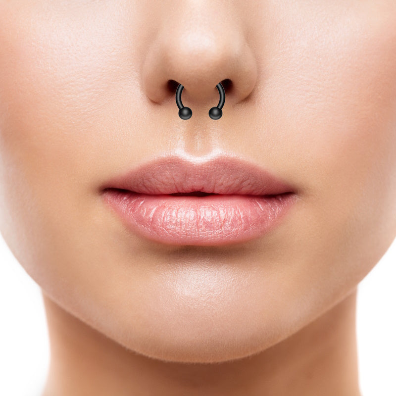 A black horseshoe septum ring in the septum piercing of a woman.