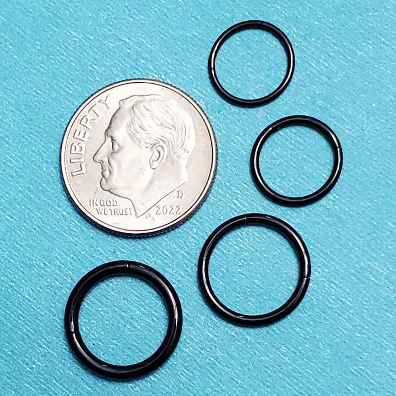 Four sizes of black titanium septum rings pictured on an aqua background next to a dime for a size comparison.