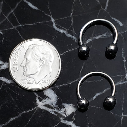 Two Circular Barbell Septum Rings 316L Surgical Steel Internally Threaded pictured next to a dime on a black marble countertop for size comparison.
