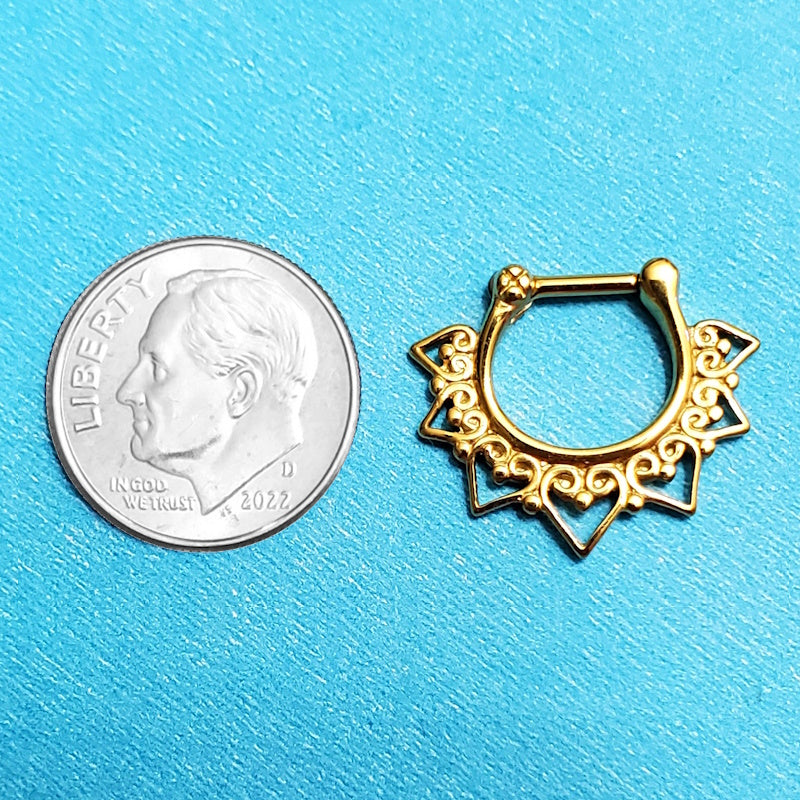 A gold plated tribal septum ring pictured on an aqua background next to a dime for a size comparison.