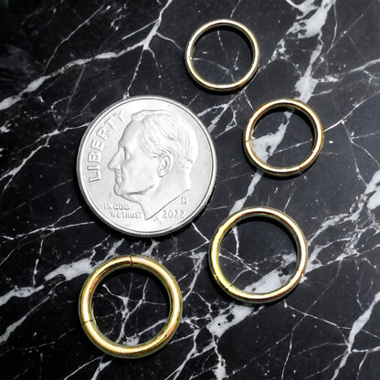 Gold Hinged Segment Septum Hoop ASTM F136 Titanium 20G 18G 16G 14G pictured on a black marble countertop next to a US dime to show size comparison.