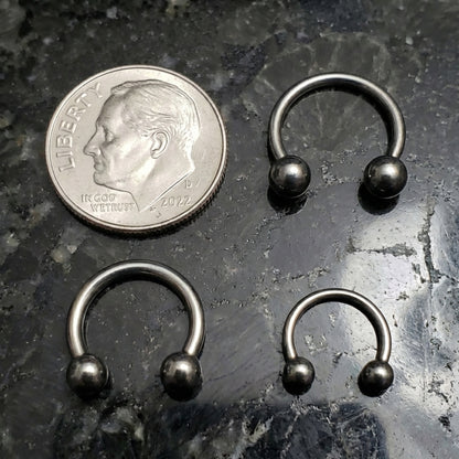 Horseshoe Septum Ring Circular Barbell 316L Surgical Steel 18G 16G 14G pictured next to a dime on a black marble countertop for size comparison.