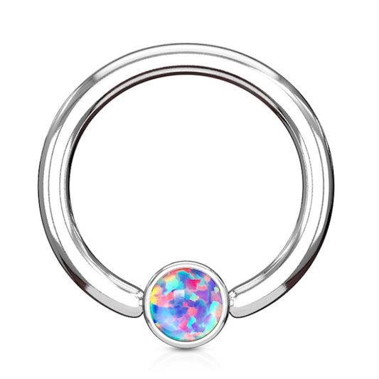 A purple opal septum ring featuring a purple synthetic opal in a cylinder shaped captive bead snaped into a surgical steel hoop  pictured against a white background.