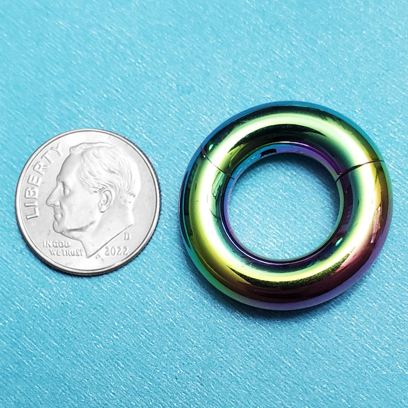 A rainbow 2g septum ring pictured on an aqua background next to a dime for a size comparison.