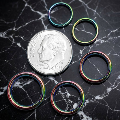 Rainbow Hinged Segment Ring 316L Surgical Steel 20G 18G 16G 14G 12G pictured next to a dime on a black marble countertop for a size comparison.