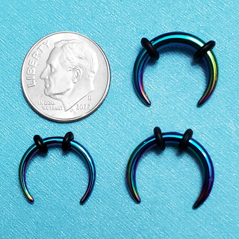 Three sizes of rainbow pincher septum rings pictured on an aqua background next to a dime for a size comparison.