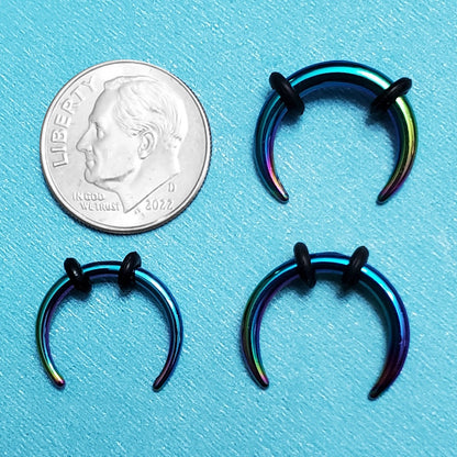 Three sizes of rainbow pincher septum rings pictured on an aqua background next to a dime for a size comparison.