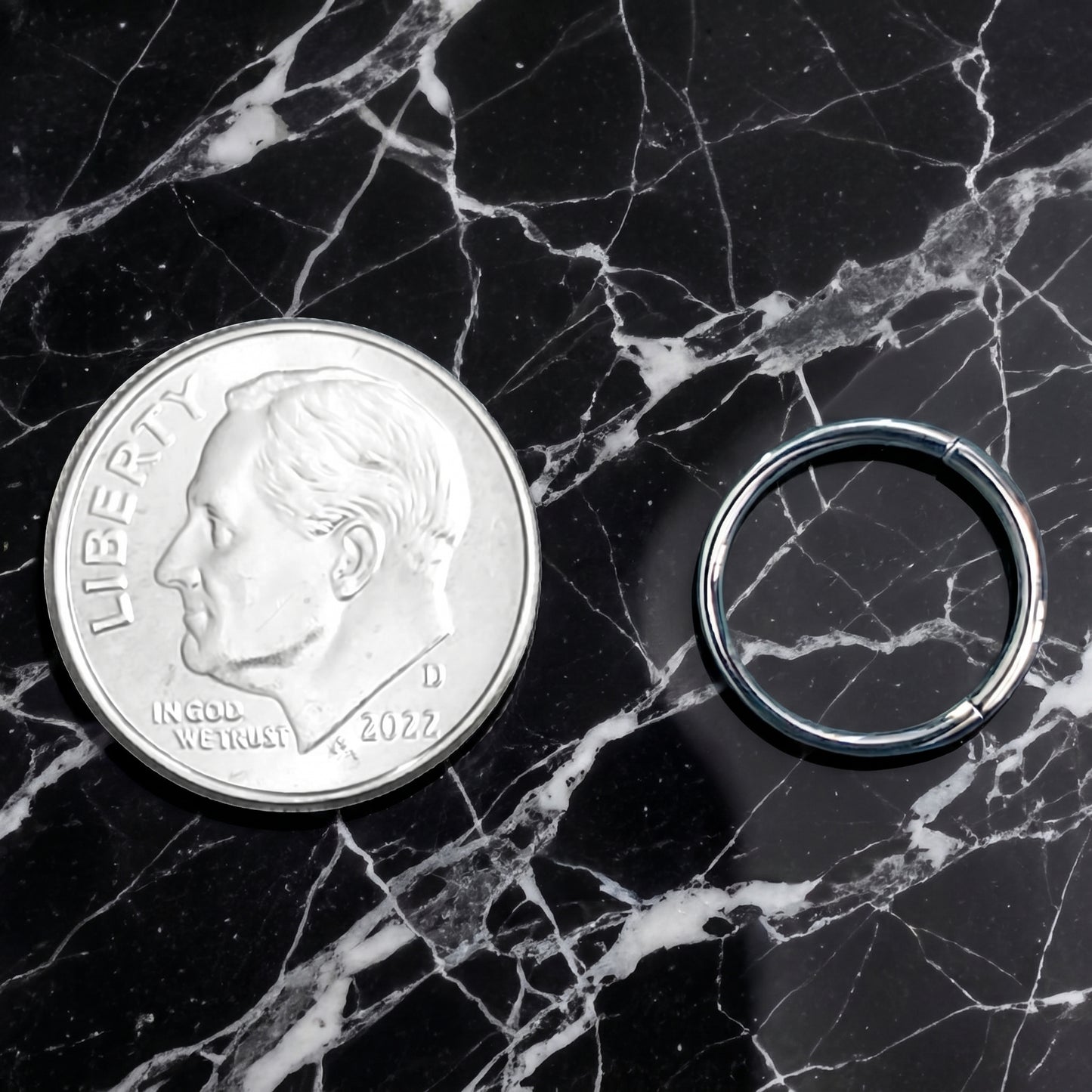 Rectangular Facet Segment Septum Hoop 16 Gauge ASTM F136 Titanium pictured next to a dime on a black marble countertop to show size comparison.
