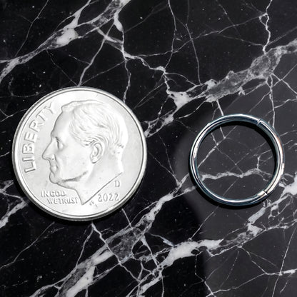 Rectangular Facet Segment Septum Hoop 16 Gauge ASTM F136 Titanium pictured next to a dime on a black marble countertop to show size comparison.