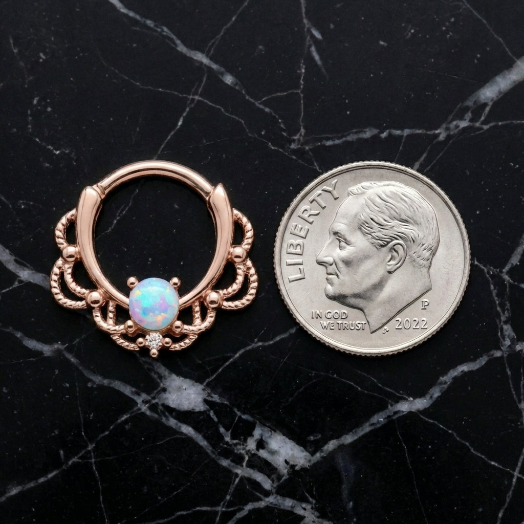 Rose Gold Filigree Opal Septum Clicker 16 Gauge 316L Surgical Steel pictured next to a dime on a black marble countertop.