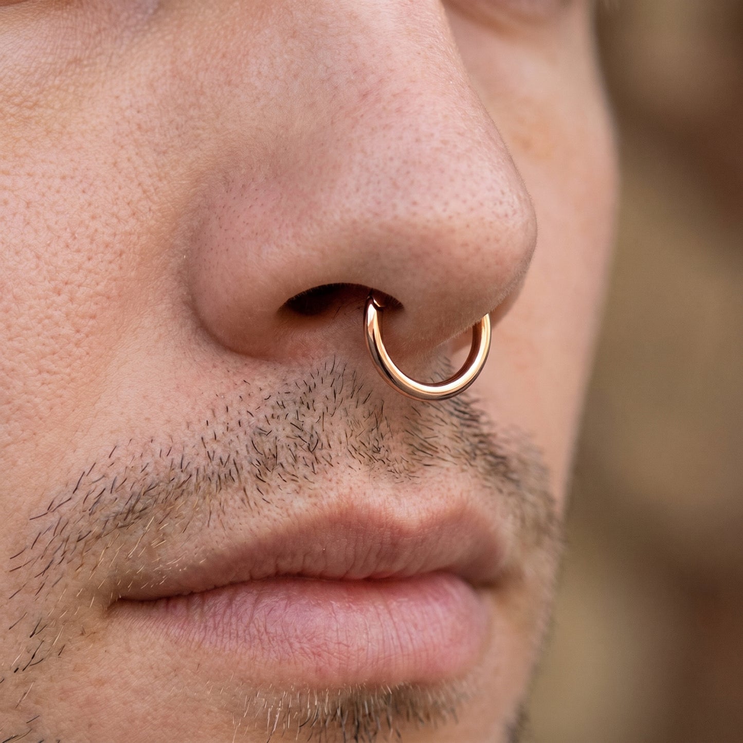 Rose Gold Hinged Segment Hoop ASTM F136 Titanium pictured in the septum piercing of a male model.