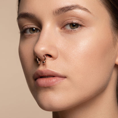 Rose Gold Horseshoe Circular Barbell Septum Ring in the septum piercing of a female model.