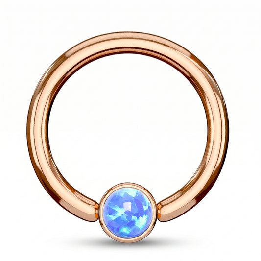 A rose gold opal captive bead septum ring featuring a synthetic blue opal on a rose gold hoop pictured against a white background.