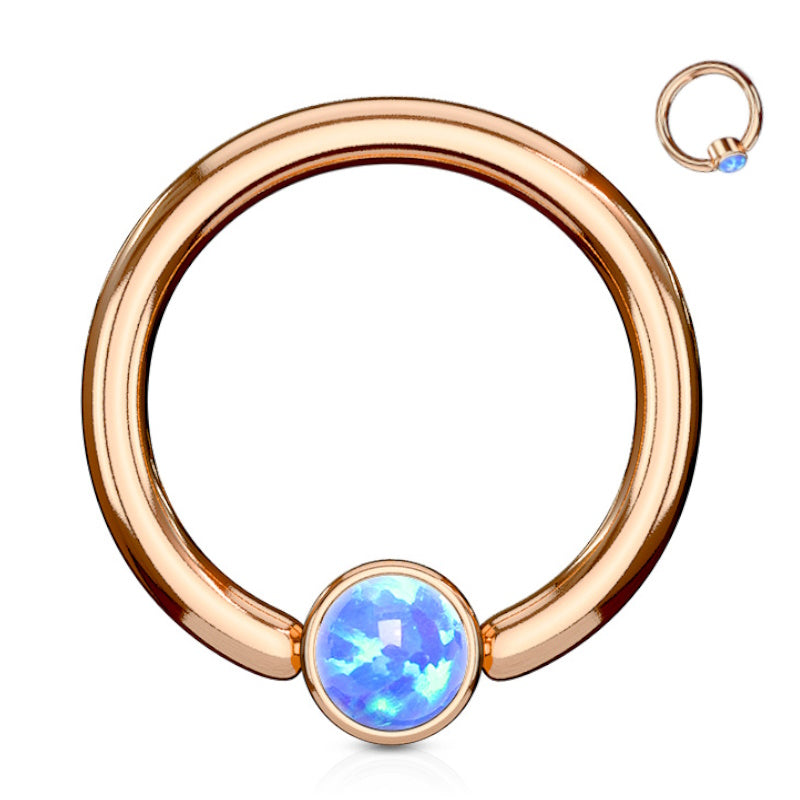 A rose gold opal septum ring featuring a synthetic blue opal on a rose gold hoop pictured against a white background.