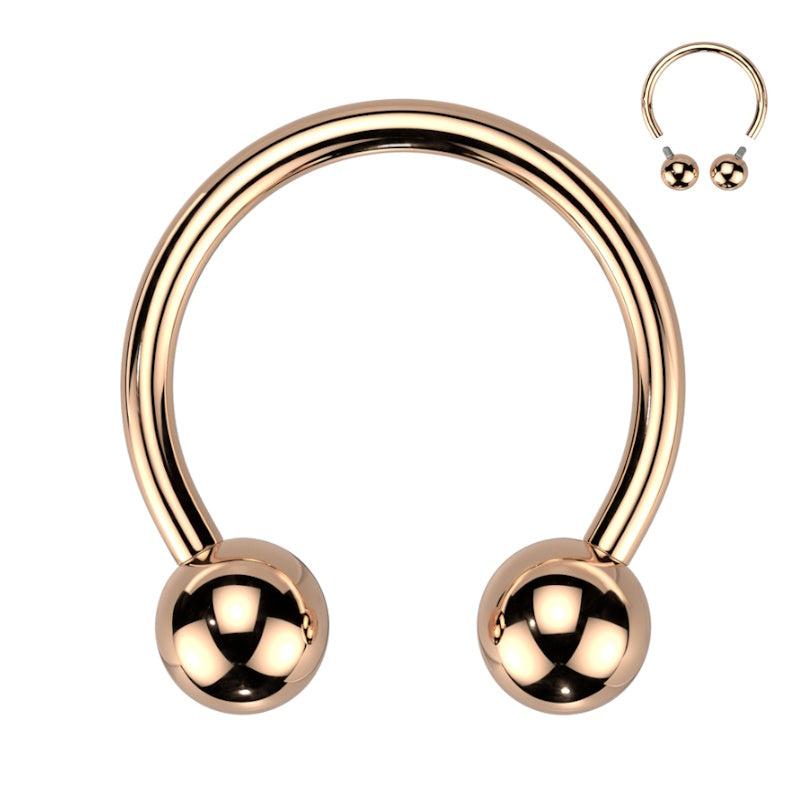 A rose gold septum horseshoe that is internally threaded with a ball on each end of the horseshoe pictured against a white background.