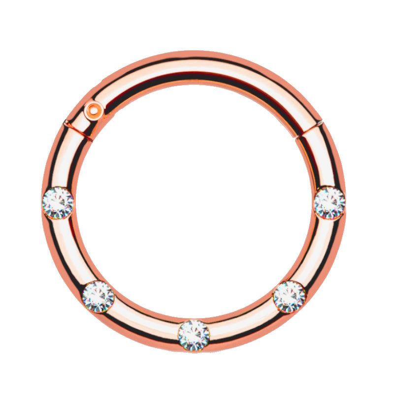 A surgical steel rose gold septum piercing ring featuring 5 front facing petite crystals pictured against a white background.