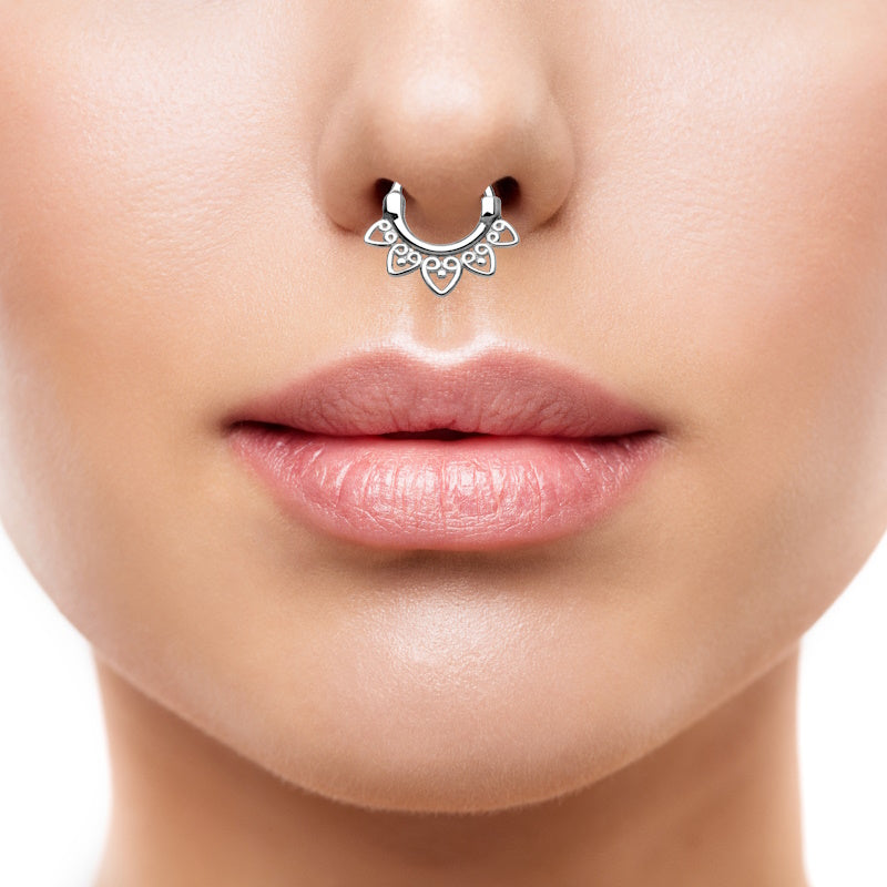 A stainless steel septum clicker featuring a tribal fan design pictured in the septum piercing of a woman.