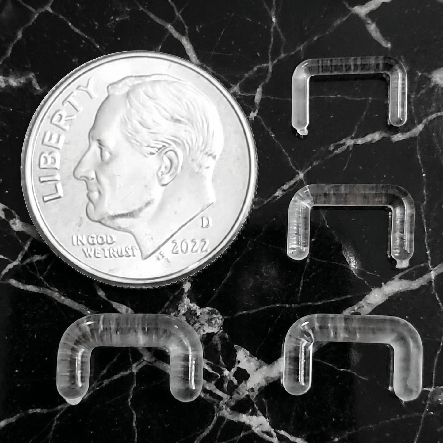 Clear Acrylic Staple Design Septum Retainer 16G 14G 12G 10G pictured next to a dime for size comparison.