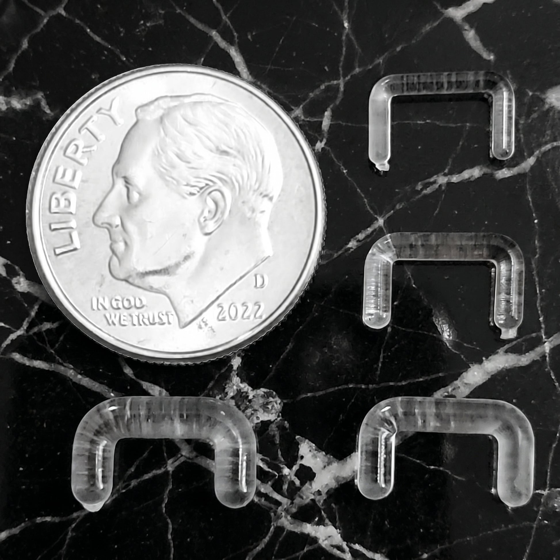 Clear Acrylic Staple Design Septum Retainer 16G 14G 12G 10G pictured next to a dime for size comparison.
