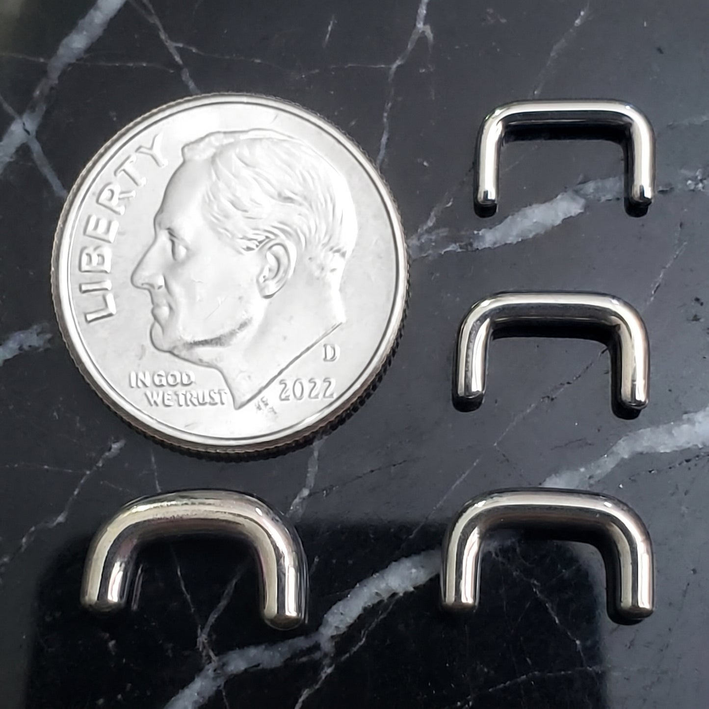 Staple Design Septum Retainer 316L Surgical Steel 16G 14G 12G 10G pictured next to a US dime on a black marble countertop.