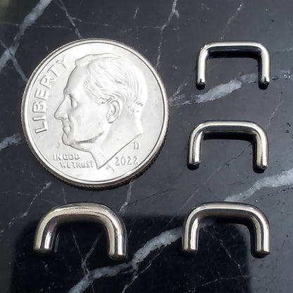 Staple Design Septum Retainer 316L Surgical Steel 16G 14G 12G 10G pictured next to a US dime on a black marble countertop.