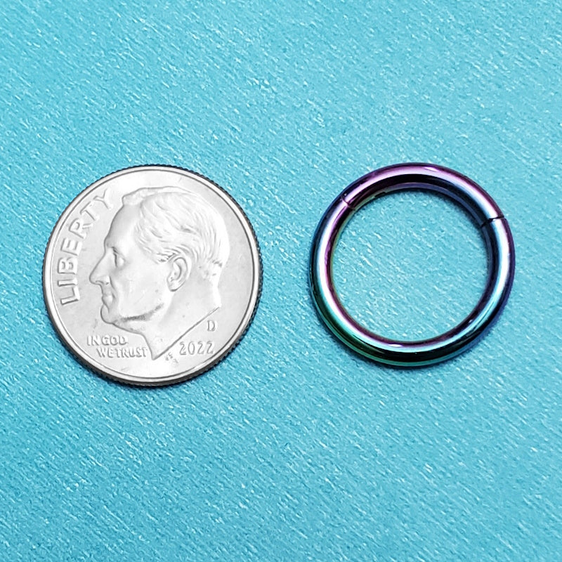 A surgical steel 12g septum ring pictured on an aqua background next to a dime for a size comparison.