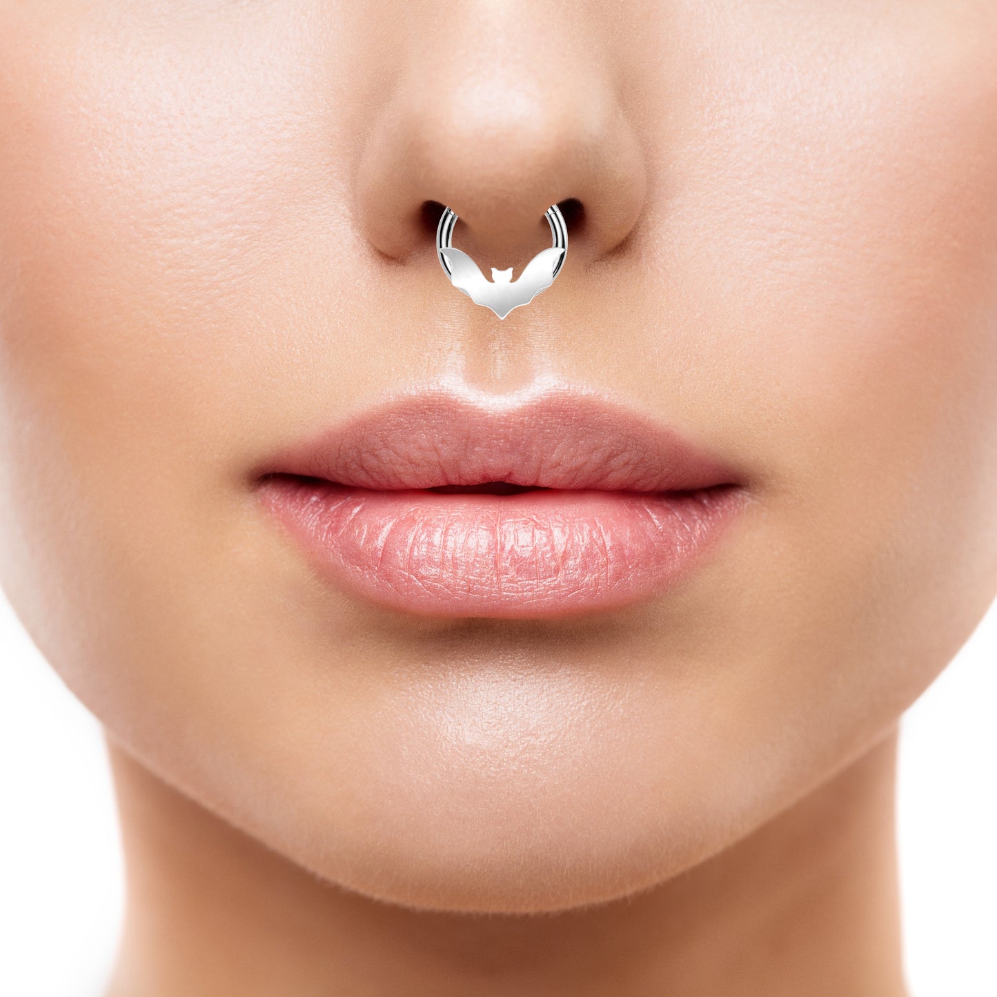 A surgical steel bat segment ring featuring a bat design on the front of a surgical steel hoop with a hinged segment style closing pictured in the septum piercing of a woman.