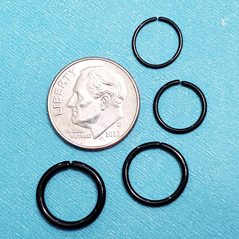 Four sizes of surgical steel black septum hoops pictured on an aqua background next to a dime for a size comparison.