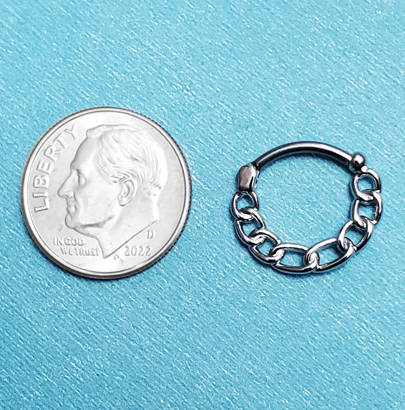 A surgical steel chain septum ring pictured on an aqua background next to a dime for a size comparison.