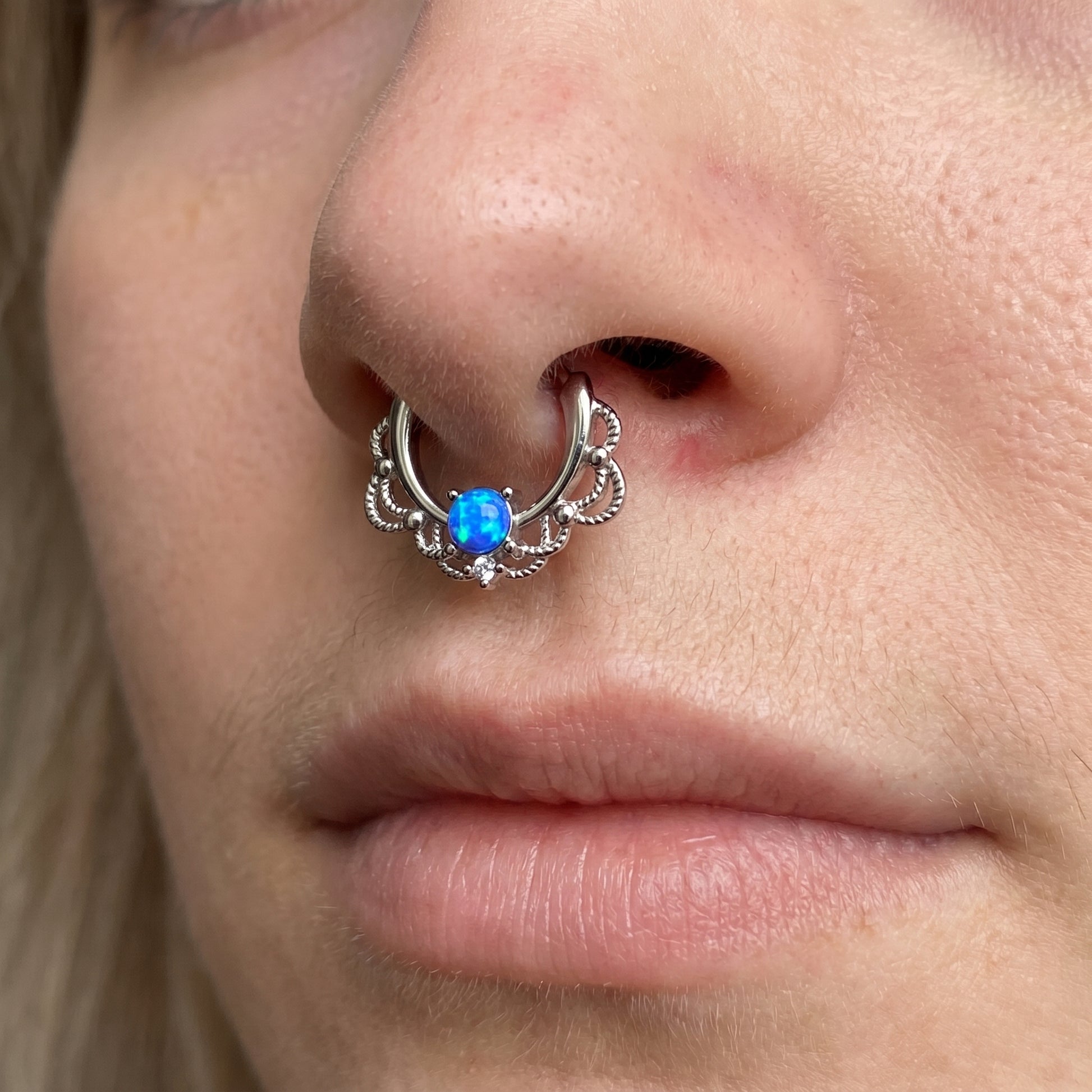 Filigree Blue Opal Septum Clicker 16 Gauge 316L Surgical Steel Brass pictured in the septum piercing of a female model.