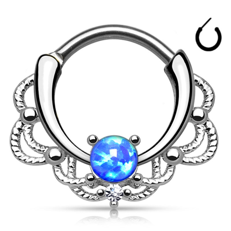 A surgical steel opal septum clicker featuring a blue opal centered against a lacy design with the piece pictured against a white background.