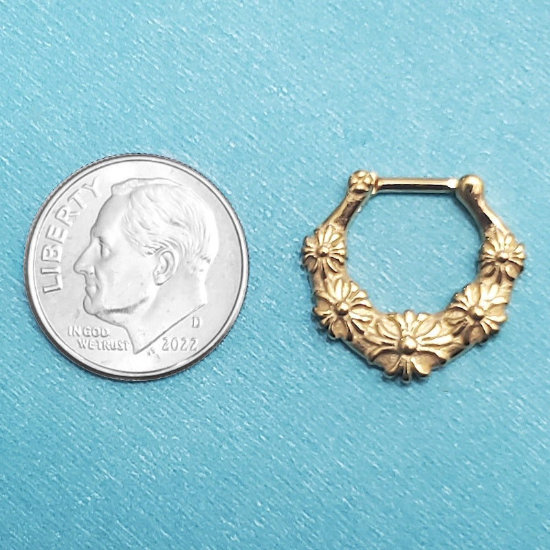 A surgical steel septum piercing clicker pictured on an aqua background next to a dime for a size comparison.