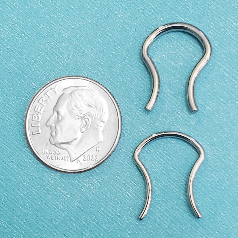 A surgical steel septum piercing retainer pictured on an aqua background next to a dime for a size comparison.