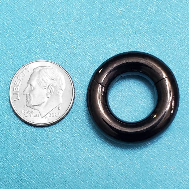 A surgical steel thick septum ring pictured on an aqua background next to a dime for a size comparison.