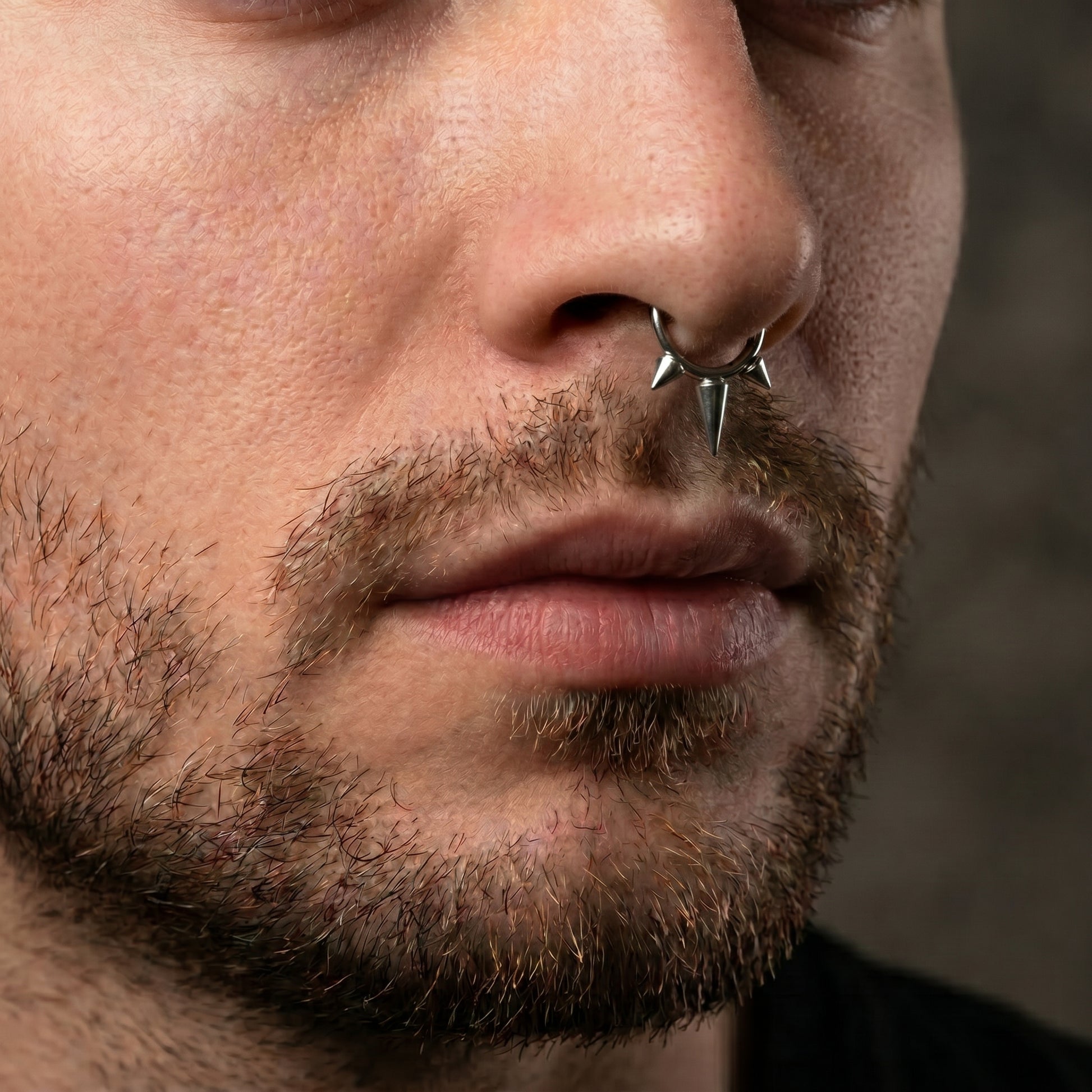 Three Spike Segment Septum Ring 16 Gauge ASTM F136 Titanium pictured in the septum piercing of a male model.