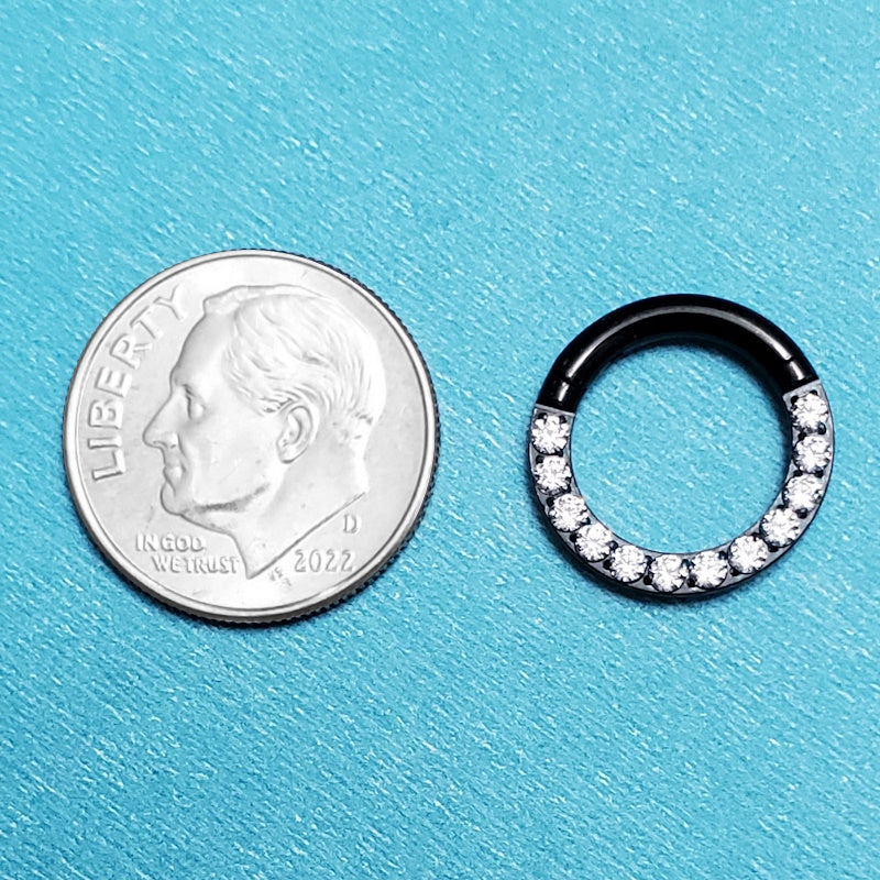 A titanium 12g segment ring pictured on an aqua background next to a dime for a size comparison.