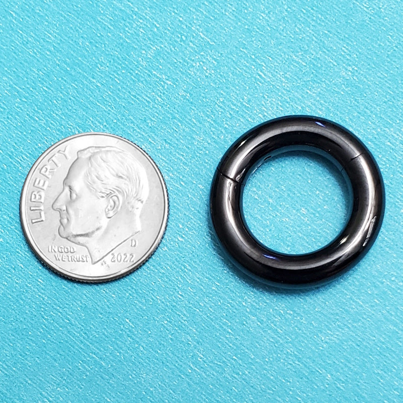 A titanium 6g septum ring pictured on an aqua background next to a dime for a size comparison.