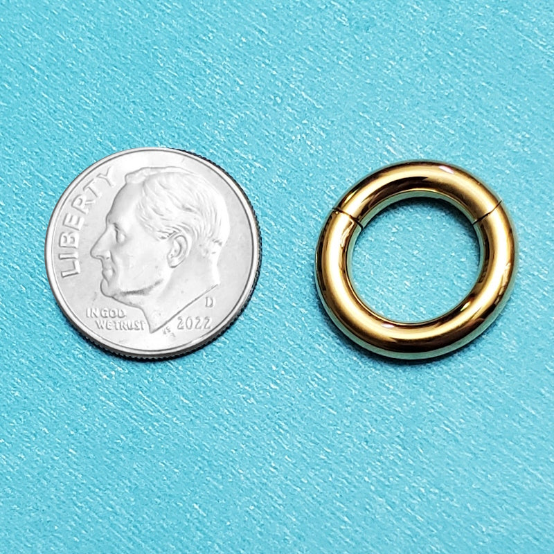 A titanium 8 gauge septum ring pictured on an aqua background next to a dime for a size comparison.