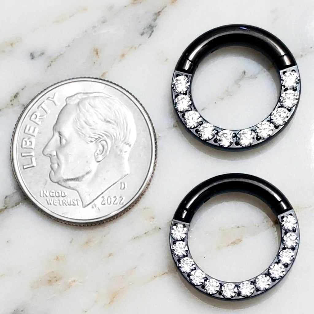 12 gauge and 10 gauge titanium black cubic zirconia septum rings pictured on a white marble countertop next to a dime for size comparison.