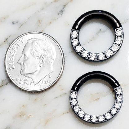 12 gauge and 10 gauge titanium black cubic zirconia septum rings pictured on a white marble countertop next to a dime for size comparison.