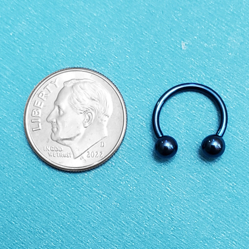 A titanium blue septum ring pictured on an aqua background next to a dime for a size comparison.