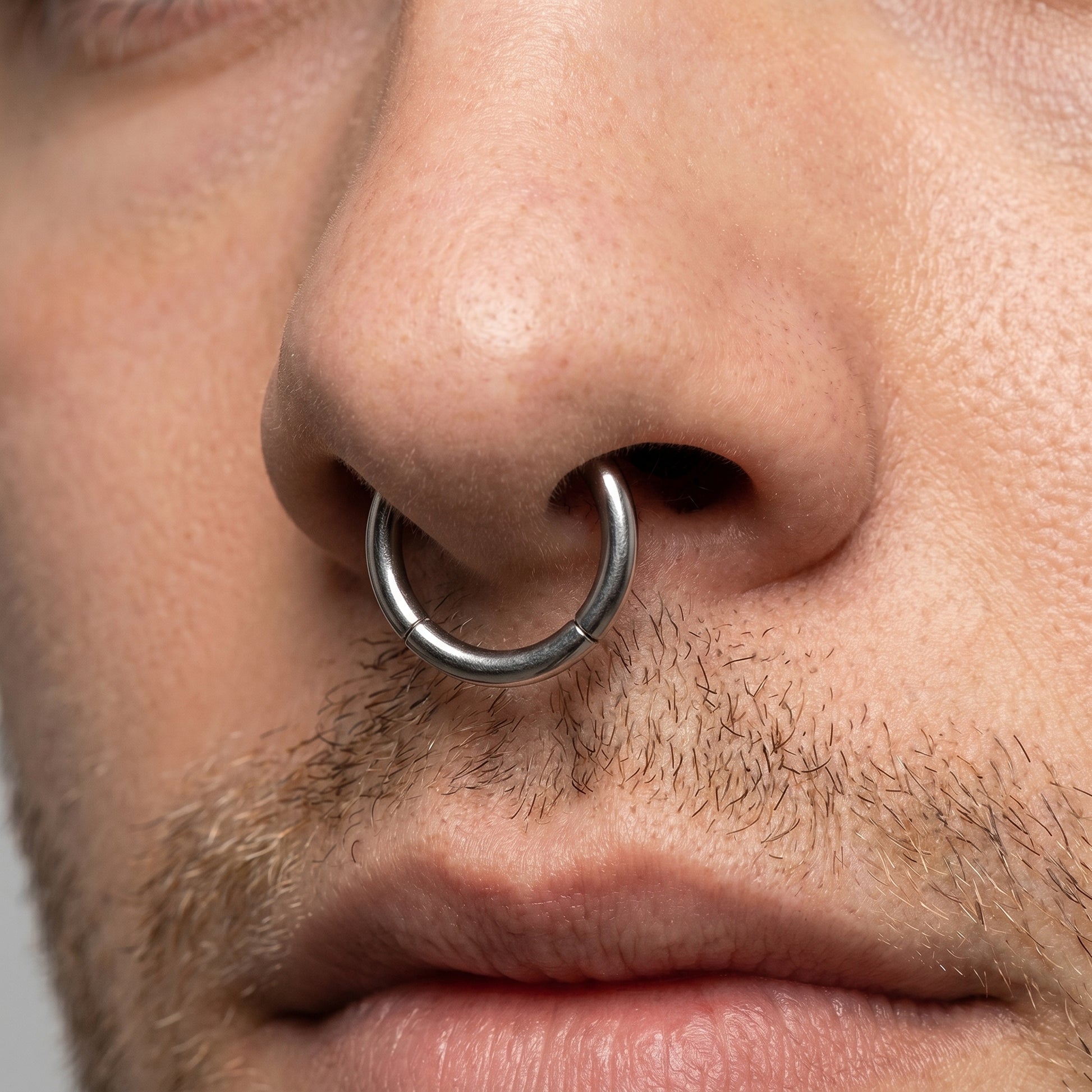 Hinged Segment Septum Ring ASTM F136 Titanium pictured in the septum piercing of a male model.